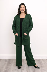 Women's forest green cable knit layering cardigan sweater with front pockets on white backdrop.