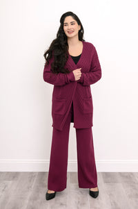 Front view of a woman wearing an extra coverage raspberry pink cable knit cardigan top.