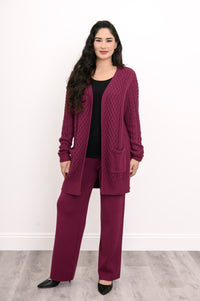 Three quarter view of a woman modeling a comfortable raspberry pink cable knit sweater for fall layering.