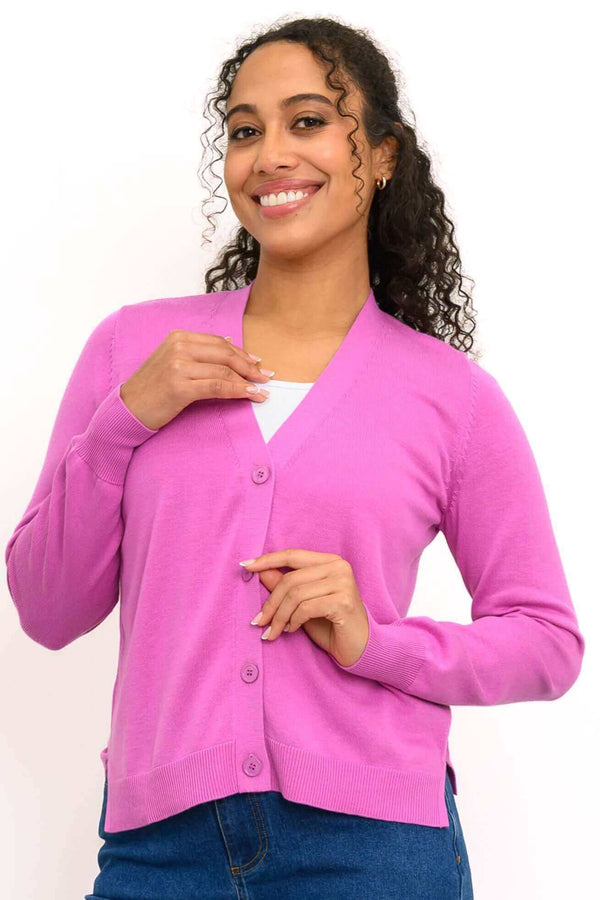 Woman wearing a pink button-up V-neck cardigan with ribbed cuffs and hem, smiling