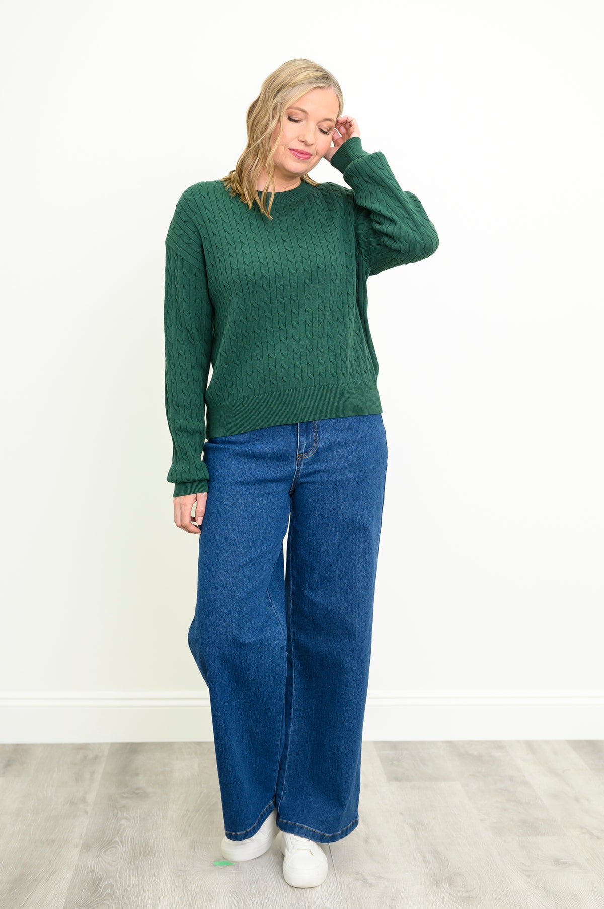 Vibrant dark green long-sleeve cotton sweater with a classic braided texture, styled with denim pants.