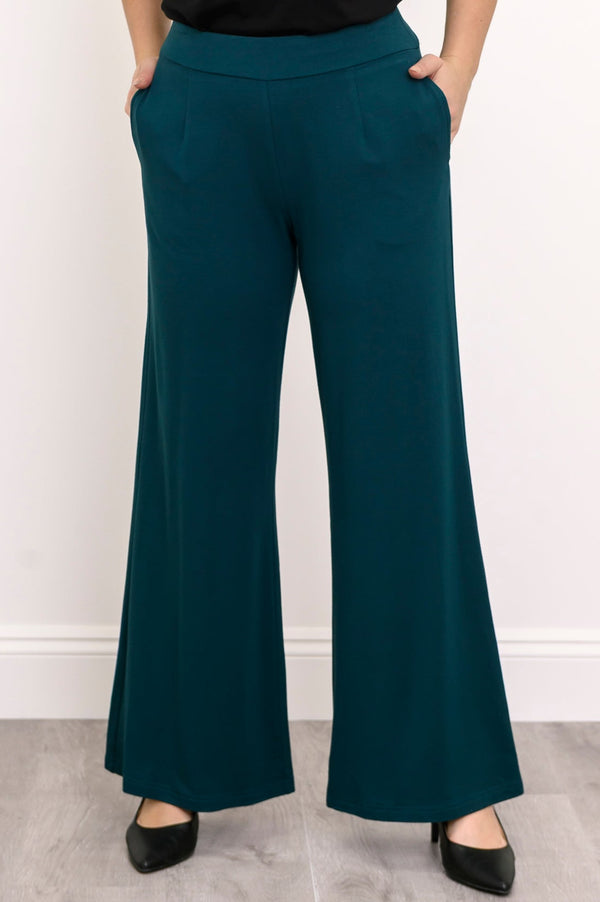 Front view of a woman wearing teal wide-leg bamboo French terry pants featuring front darts and side pockets