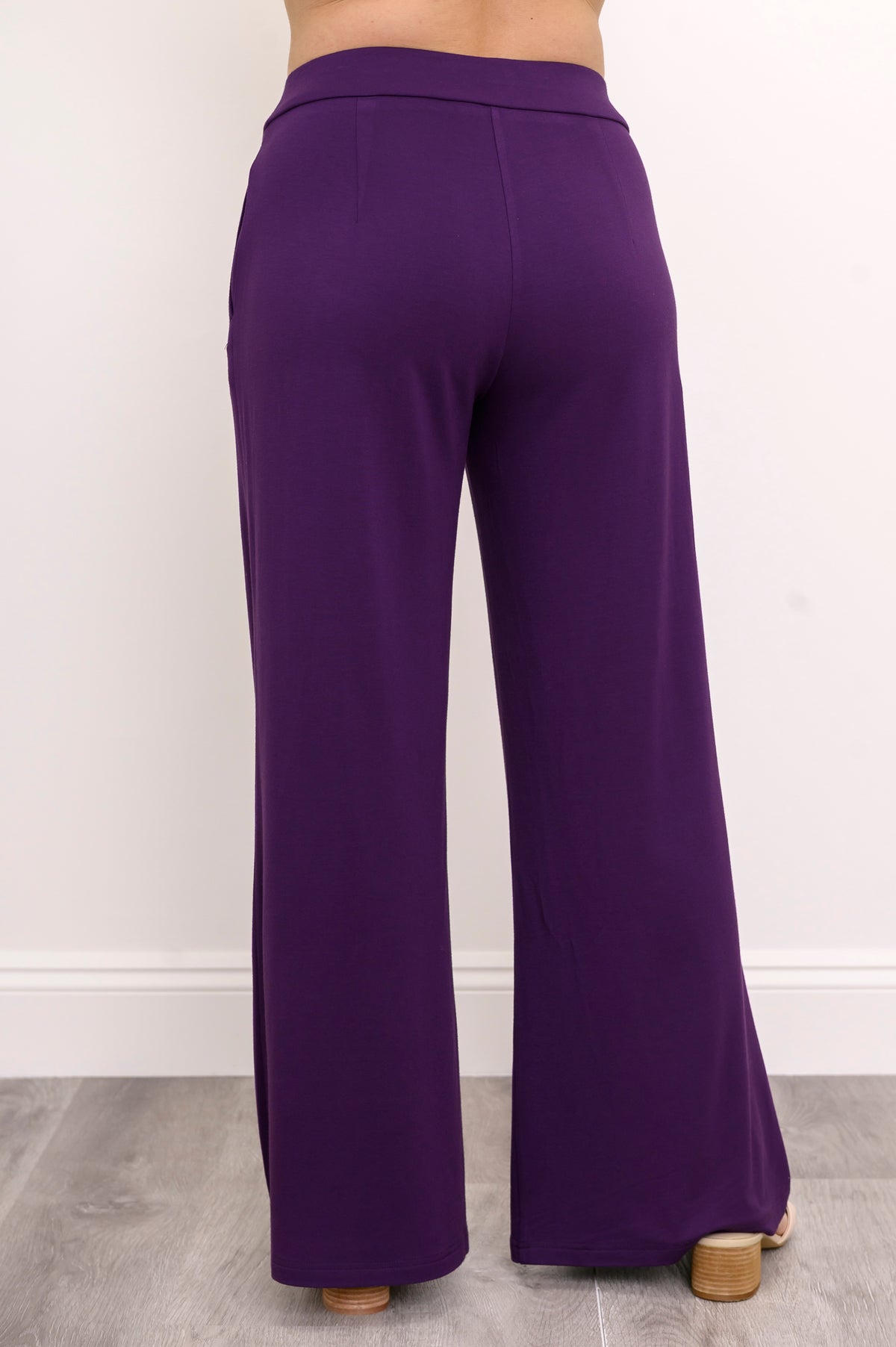 Back view of a woman wearing royale purple wide-leg bamboo French terry pants with shaping rear darts.