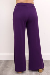 Back view of a woman wearing royale purple wide-leg bamboo French terry pants with shaping rear darts.