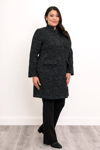 Side view of woman wearing long black coat with mandarin collar and flap pockets