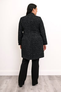 Back view of woman wearing long wool coat in black with white sparkles and split hem