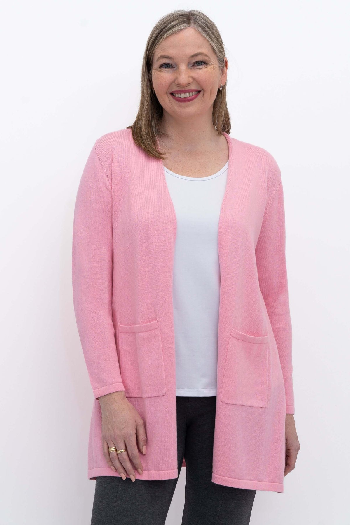 Front view of woman wearing pink open cardigan with patch pockets