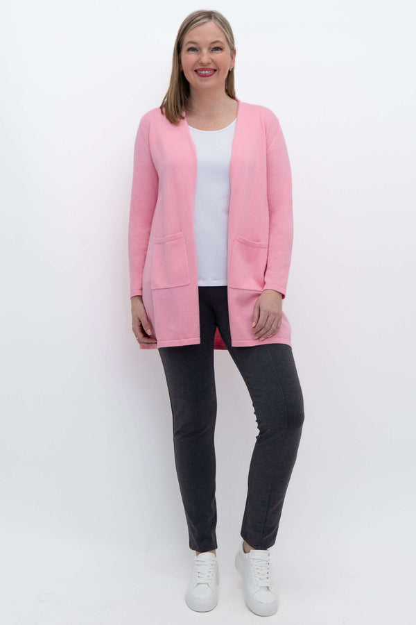 Full body view of woman in pink cardigan paired with dark pants and white sneakers