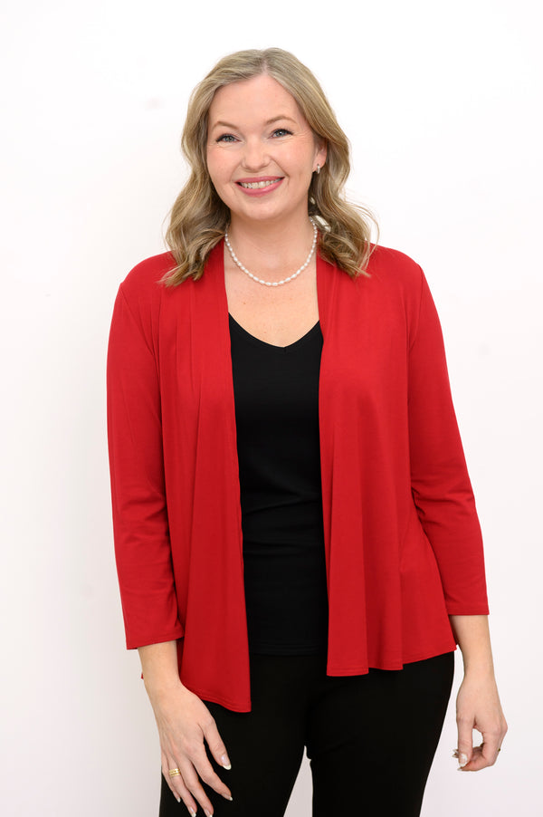 Front view of woman wearing a red cardigan, black top, and black pants on a white background