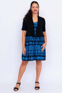 Front view of woman in blue elephant dress with black cardigan and black sandals