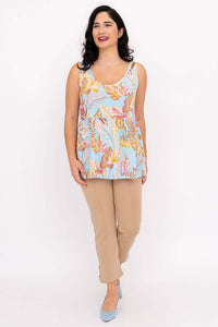Woman smiling in tropical leaf print tank top and beige pants, front view