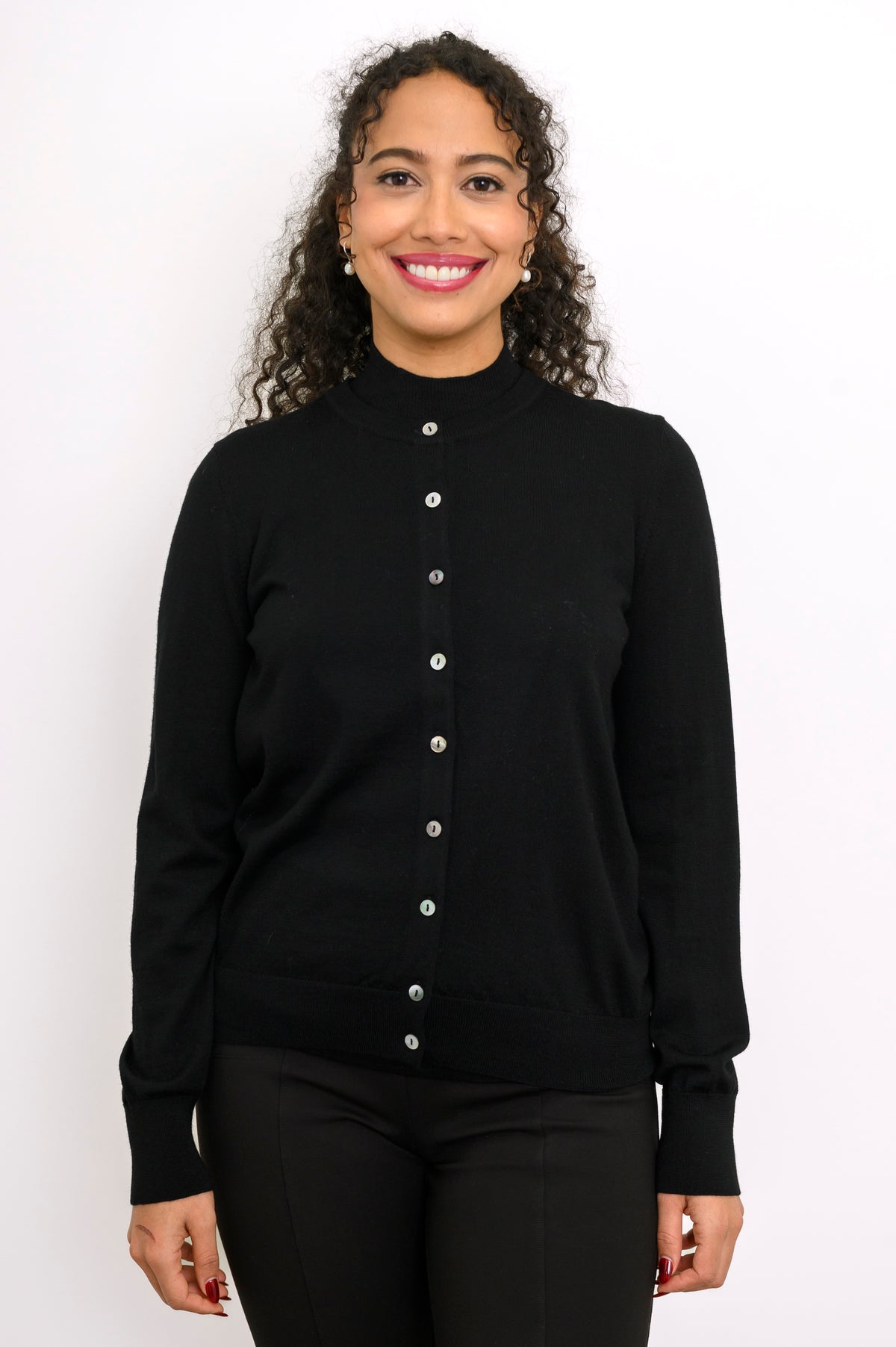 Close up front view of a smiling woman wearing a black fine knit merino wool crewneck cardigan.