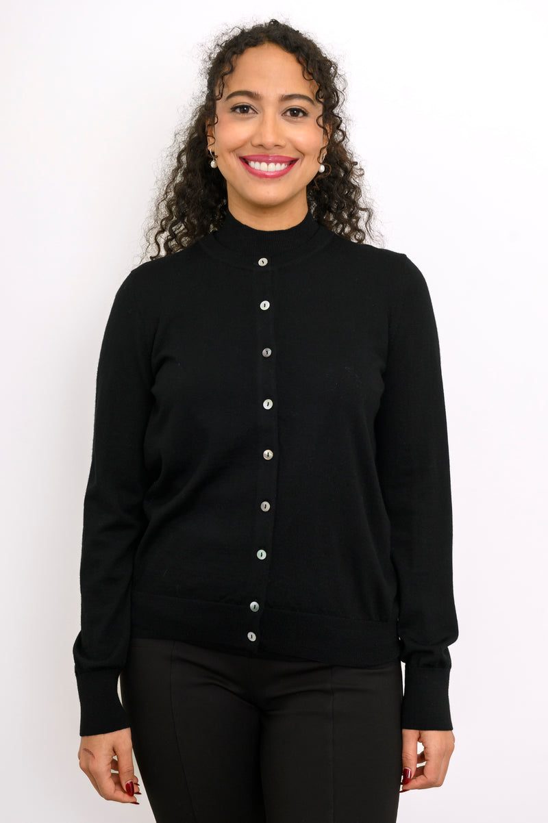 Close up front view of a smiling woman wearing a black fine knit merino wool crewneck cardigan.