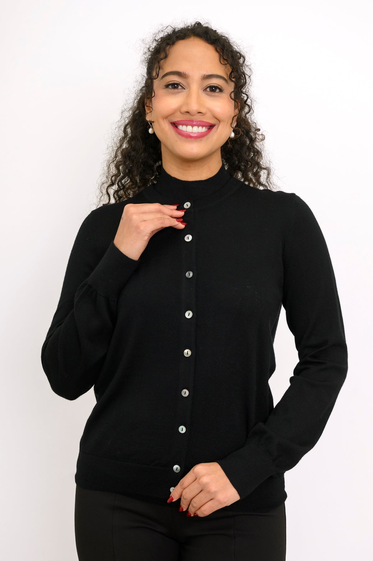 Woman modeling a monochromatic black outfit featuring a long sleeve crewneck cardigan and trousers.