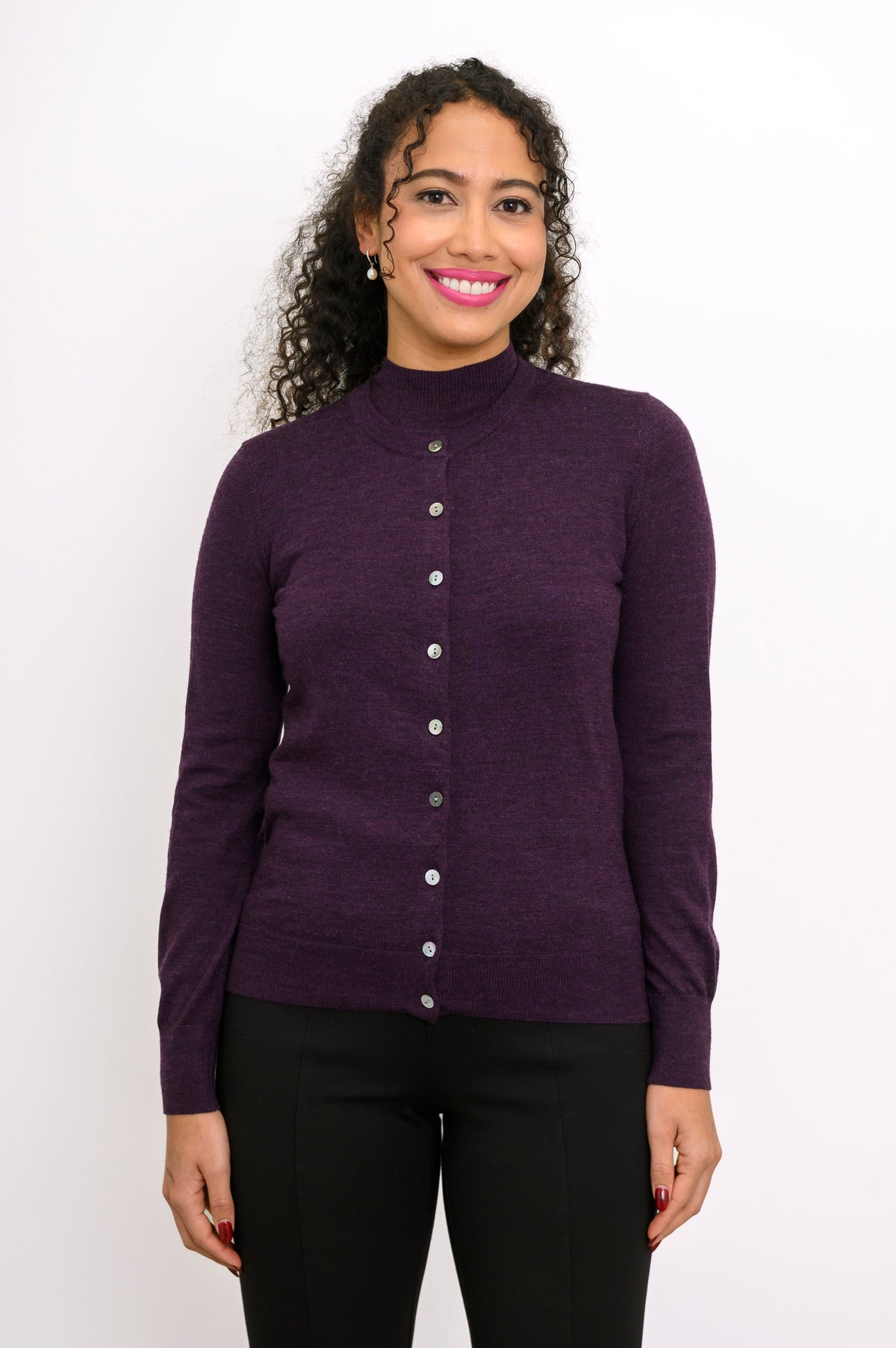 Front view of woman wearing a purple cardigan on a purple top and black pants against a white background