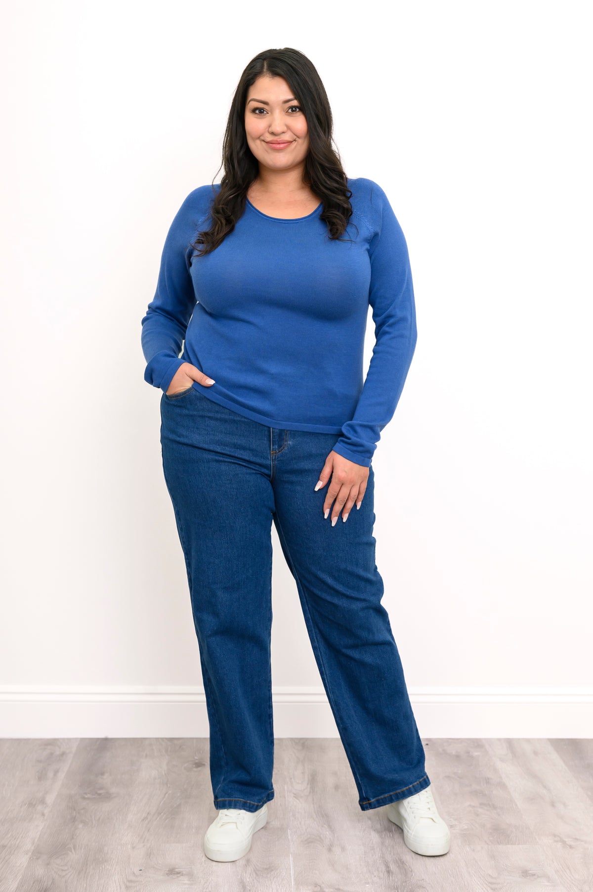 Smiling woman wearing a pacific blue knit sweater with a loose scoop neckline and comfortable long raglan sleeves.