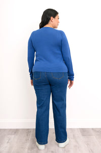 Back view of a pacific blue raglan sweater, showcasing a seamless rear panel, long sleeves, and dark denim jeans.