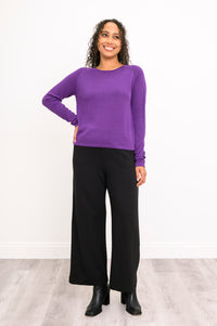 Front-facing view of a women's deep violet scoop neck knit top and dark pants, showcasing a classic autumn look.