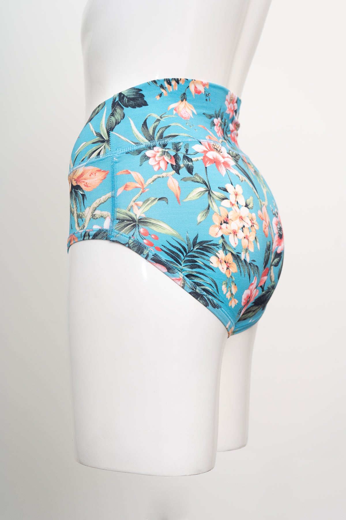 Turquoise high waist bamboo briefs with coral and black botanical prints displayed on a white mannequin model.