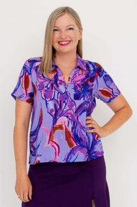 Woman modeling a short sleeve purple and magenta abstract print zip collar top