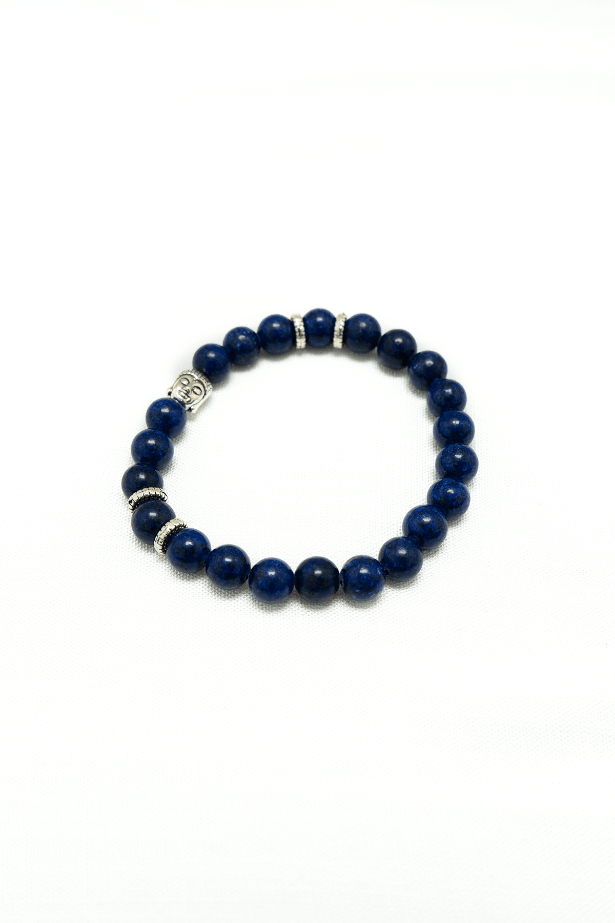 Lapis Lazuli bead bracelet with Buddha charm and silver spacers on a white background