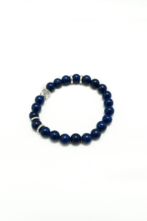 Lapis Lazuli bead bracelet with Buddha charm and silver spacers on a white background