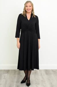 Woman wearing long black dress and black heels on a white background, front view
