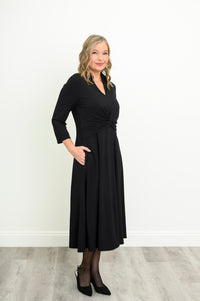 woman wearing a black bamboo midi dress with a twist-front waist, V-neckline, and 3/4 sleeves