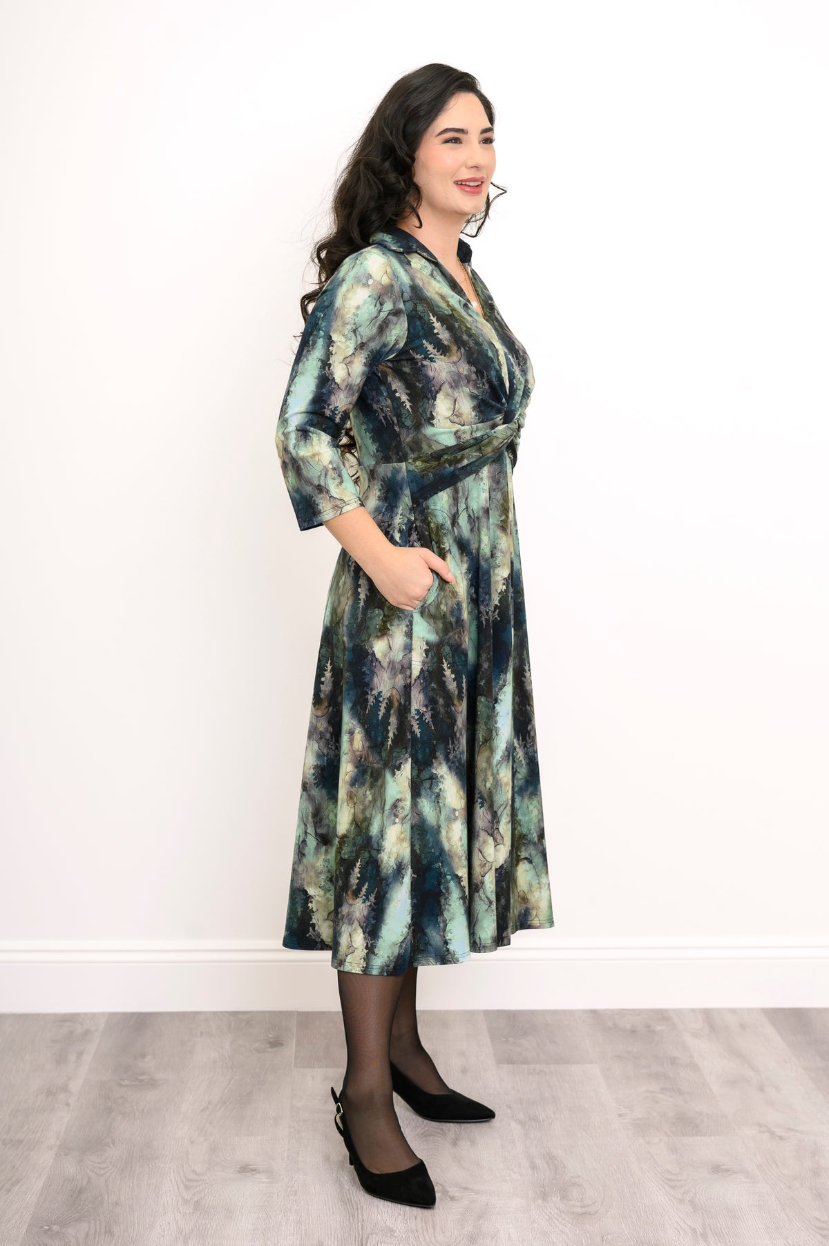 Long-sleeve printed knit midi dress with a twisted waist detail and full skirt, styled with black heels.