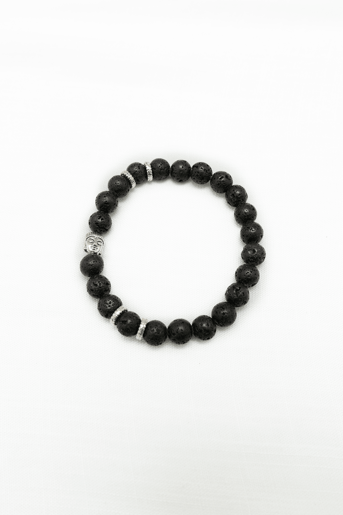 Black lava stone beaded bracelet with Buddha head and silver accents on white background