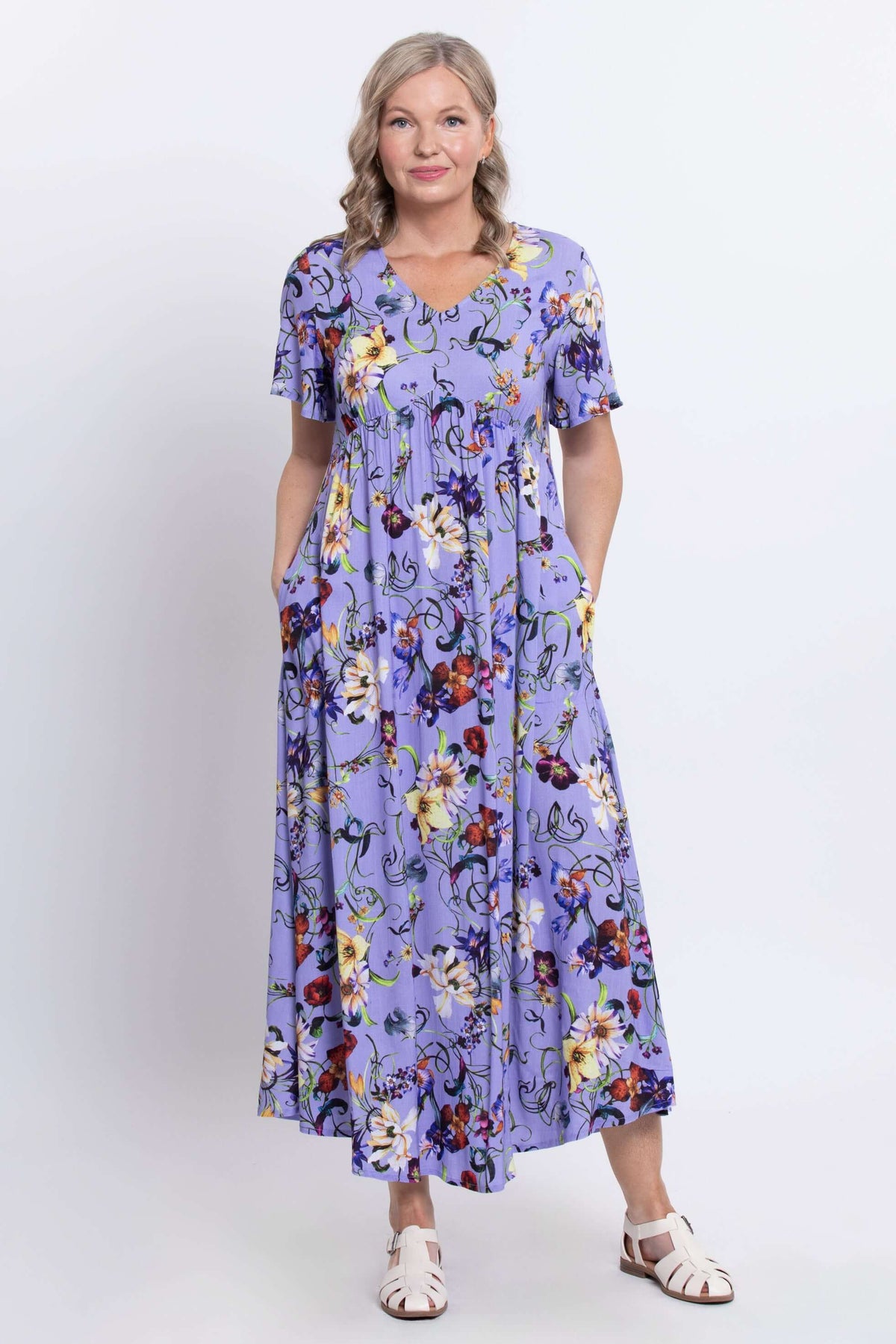 Woman wearing a lavender floral maxi dress with flutter sleeves, standing facing forward