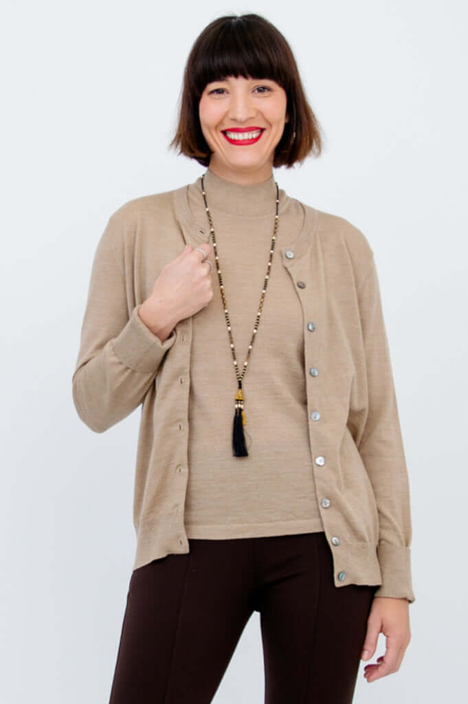 Woman layering a beige mock neck sweater with a matching button-up cardigan