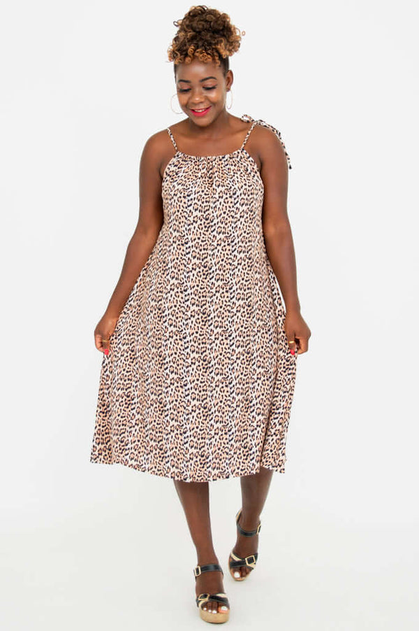 Woman posing in a sleeveless leopard print beach dress with adjustable tie shoulder