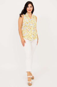Model walking in yellow floral sleeveless shirt with white pants and sandals