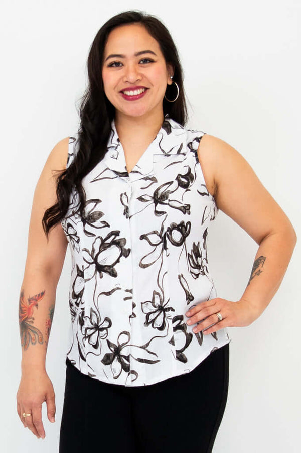 Woman wearing a sleeveless collared black and white floral print shirt, smiling