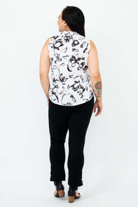 Back view of a woman in a sleeveless black and white print shirt and black pants