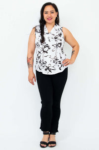 Full body view of a woman in a sleeveless black and white print shirt and black pants