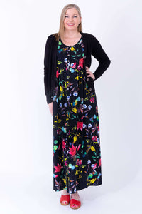 Woman in floral bamboo maxi dress with black cardigan and red sandals, hands on hips