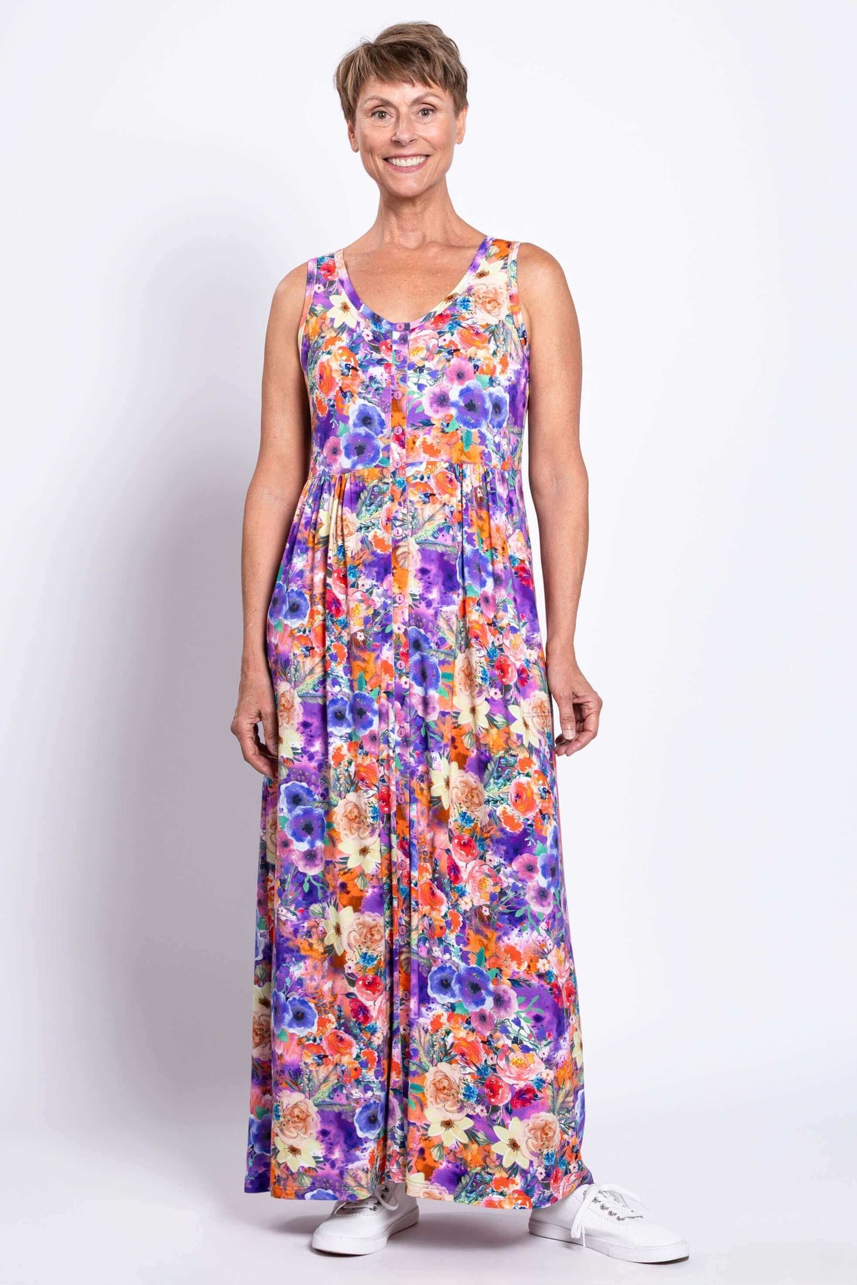 Front view of a woman modeling a maxi-length, colorful floral sleeveless dress