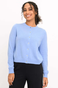 Woman wearing a light blue cashmere cardigan with crew neckline and button front, closeup view