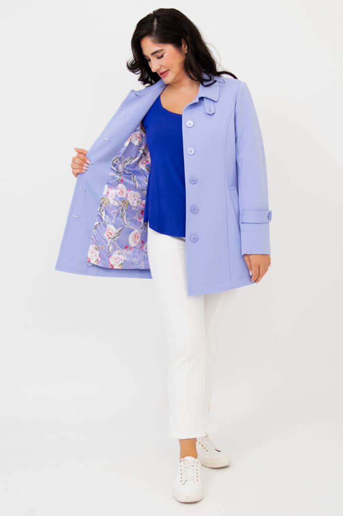Woman showing floral lining of light blue tulip jacket, paired with blue top