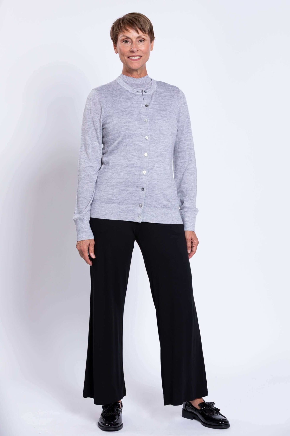Woman wearing a light grey button-up merino wool cardigan with black pants