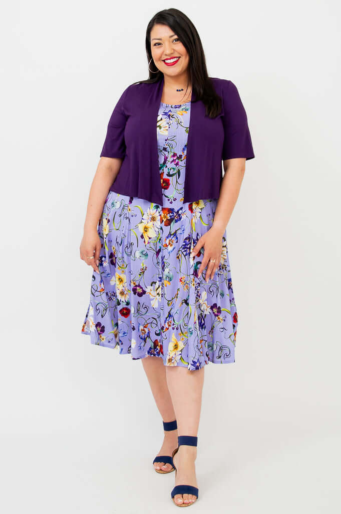 Woman in a lilac floral dress layered with a short-sleeve purple cardigan