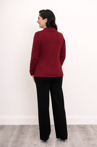 Back view of a woman wearing a fitted hip-length burgundy cotton sweater showcasing the clean tailoring and shoulder fit.