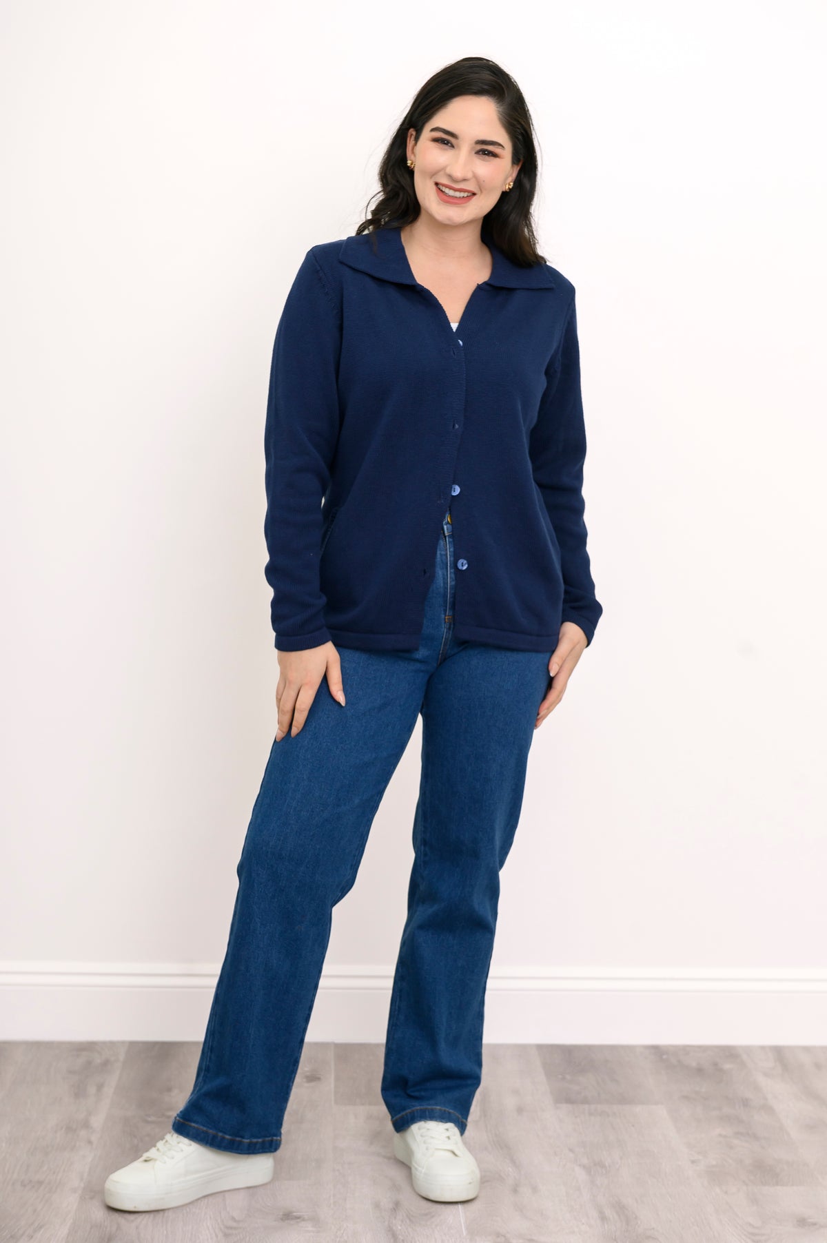 Front view of a woman wearing a classic buttoned navy knit shirt sweater styled with dark blue denim.