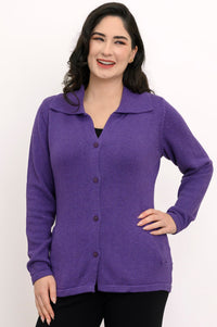 Smiling woman wearing a violet knit cardigan with a classic fold-over collar, front portrait view on white backdrop.
