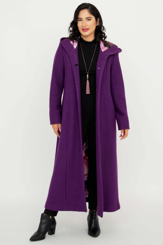 Woman standing in a long purple hooded coat, open to reveal patterned lining