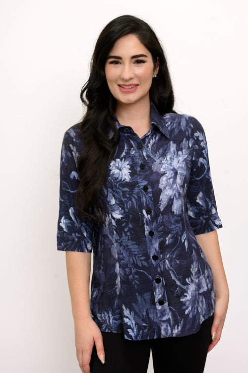 Woman wearing a navy blue floral patterned shirt and black pants against a white background, front view