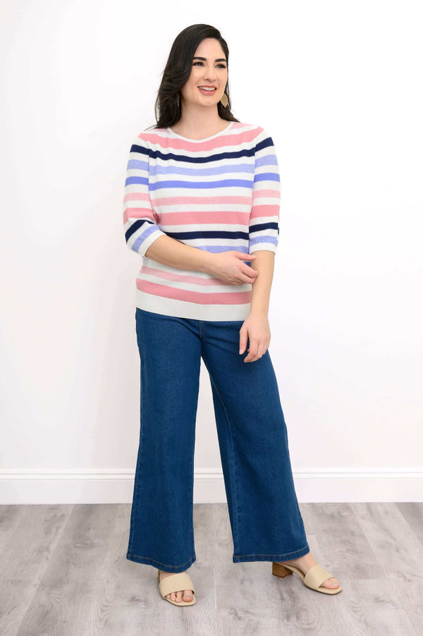 Model wearing Louisa Sweater with pink, navy, lilac, and white stripes and blue wide-leg jeans