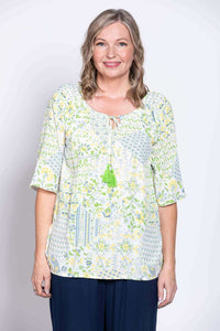 Front view of woman wearing Luna Boho Peasant Top with floral pattern and green tassel tie